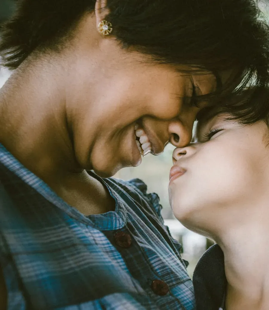 A mother and her young son touching noses and smiling together